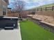 Turfed backyard with hot tub, retaining wall, and hillside view at 1815 Avery Way, Castle Rock, CO 80109