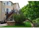 Secluded backyard with mature trees, stone retaining wall, stairs to a balcony, and an outdoor dining set at 2819 Canyon Crest Dr, Highlands Ranch, CO 80126