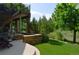 Landscaped backyard featuring a patio with stone accents, a deck, green grass, and mature trees at 2819 Canyon Crest Dr, Highlands Ranch, CO 80126