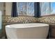 Close-up of a large white bathtub with a faucet, tile backsplash, and views of the exterior at 16123 Quarry Hill Dr, Parker, CO 80134