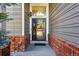 View of front door with security door, brick trim, and gray siding at 16123 Quarry Hill Dr, Parker, CO 80134