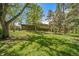 Large grassy backyard with mature trees and a green two-story home with a brick addition at 13955 W 26Th Ave, Golden, CO 80401