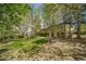 Large, grassy backyard with mature trees, a patio, and a green, two-story house in the background at 13955 W 26Th Ave, Golden, CO 80401
