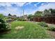 Spacious backyard with a lush lawn, wooden fence, mature trees, a wooden gate, and well-manicured garden beds at 9220 Lowell Blvd, Westminster, CO 80031