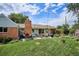 Spacious backyard with lush green lawn, brick patio, outdoor seating, well-manicured garden, and privacy fence at 9220 Lowell Blvd, Westminster, CO 80031
