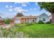 Charming brick home boasts a lush, well-manicured front yard with colorful flowerbeds and mature trees at 9220 Lowell Blvd, Westminster, CO 80031