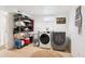 Bright laundry room featuring modern washer and dryer, tiled floor, shelving, and laundry-themed decorations at 9220 Lowell Blvd, Westminster, CO 80031