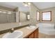 A bright bathroom featuring a double sink vanity, soaking tub, glass shower, and a large mirror at 3619 Estates Cir, Larkspur, CO 80118