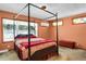 Bedroom featuring a cozy canopy bed, carpeted floors, two windows, and an eye-catching stain-glass window at 3619 Estates Cir, Larkspur, CO 80118