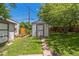 Backyard with a storage shed, a manicured lawn, mature trees and a concrete walkway at 710 Raleigh St, Denver, CO 80204