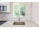 Close up of the kitchen sink, faucet, and countertop with hexagon backsplash and a window overlooking the yard at 710 Raleigh St, Denver, CO 80204