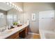 Bathroom featuring double sinks, oak cabinetry, an oversized mirror, and a tub at 4175 S Andes St, Aurora, CO 80013