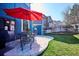 Outdoor patio featuring a table, chairs, a red umbrella, and access to a grass backyard with wood fence at 4175 S Andes St, Aurora, CO 80013