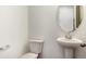 Modern powder room features a pedestal sink, toilet, and decorative oval mirror at 8339 Snake River St, Littleton, CO 80125