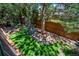 Backyard featuring lush green landscaping, decorative rock bed, mature trees, and a wood privacy fence at 5416 S Hannibal Ct, Centennial, CO 80015