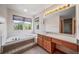 Bright bathroom featuring a soaking tub under a window and vanity with light wood cabinets at 5416 S Hannibal Ct, Centennial, CO 80015