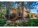 Exterior side view of a two-story home showcasing deck, landscaping, and lush greenery with mature trees at 5416 S Hannibal Ct, Centennial, CO 80015