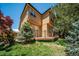 Exterior view of a two-story home with a deck, landscaping, and mature trees on a bright sunny day at 5416 S Hannibal Ct, Centennial, CO 80015