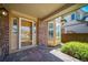 Inviting front porch featuring brick accents, decorative windows, a wooden front door, and manicured landscaping at 5416 S Hannibal Ct, Centennial, CO 80015