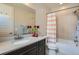 Well-lit bathroom featuring a shower-tub combo, modern sink, dark cabinets, and a large mirror at 10526 Fairhurst Way, Highlands Ranch, CO 80126