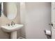 This powder bath features a pedestal sink, silver faucet, round mirror and a light beige wall at 10526 Fairhurst Way, Highlands Ranch, CO 80126