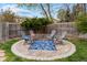 Backyard patio with circular brick pavers, four chairs, and outdoor rug, surrounded by a wooden fence and green grass at 5310 S Flanders Way, Centennial, CO 80015