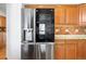 Stainless steel refrigerator nestled amongst wooden cabinetry and tile backsplash at 12899 W Aqueduct Ave, Littleton, CO 80127