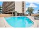Outdoor swimming pool with lounge chairs at the University Park Tower with a clear blue sky and beautiful trees at 2225 Buchtel Blvd # 208, Denver, CO 80210