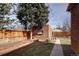 Backyard featuring a brick garage, garden beds, and grass at 1280 Fairfax St, Denver, CO 80220