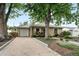 Single-story home featuring a long driveway, garage, and beautifully landscaped front yard with mature trees at 2925 S Harrison St, Denver, CO 80210
