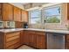 Bright kitchen featuring wood cabinets and stainless steel dishwasher under large windows at 2938 Wolfensberger Rd, Sedalia, CO 80135