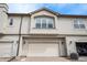 Townhome exterior featuring a two-car garage, beige paint, and complementary stone accents at 6617 S Forest Way # E, Centennial, CO 80121
