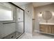 Modern bathroom with a glass shower, light gray tiling, sleek fixtures, and a vanity with a round mirror at 363 Lima St, Aurora, CO 80010