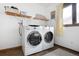 Well-lit laundry room with front loading washer and dryer and wooden shelving at 1331 Alpine St, Longmont, CO 80504