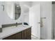 Modern bathroom featuring a stylish vanity, round mirror, and tiled shower area at 2824 W Parkside Pl, Denver, CO 80221