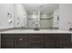 Bathroom featuring double sinks with wood cabinets, a large mirror, and a tiled shower at 2824 W Parkside Pl, Denver, CO 80221