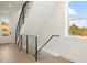 A modern staircase with sleek black railings, wooden floors, and natural light from a nearby window at 4650 W 9Th Ave, Denver, CO 80204