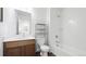 Bright bathroom featuring a wood vanity, toilet, and tiled tub with shower at 9756 Ash Ln, Thornton, CO 80229