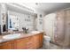 Bathroom featuring a dual sink vanity, large mirror with decorative lighting, and a shower with a floral curtain at 5534 Lewis St # 202, Arvada, CO 80002