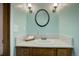 Cozy powder room featuring a marble countertop and oval mirror with modern vanity lighting at 70 Long Bow Cir, Monument, CO 80132