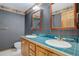 Retro bathroom featuring green plaid wallpaper, double sink vanity with teal tile, and vintage charm at 70 Long Bow Cir, Monument, CO 80132