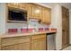 Basement wet bar featuring oak cabinets, a microwave, stainless steel mini-fridge, and a convenient countertop sink at 70 Long Bow Cir, Monument, CO 80132