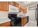 Functional kitchen features a black range oven, microwave, and wood cabinetry at 857 S Van Gordon Ct # G208, Lakewood, CO 80228