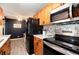 Kitchen with black appliances, wood cabinets, tiled backsplash, and an adjacent dining area at 2325 S Linden Ct # 101, Denver, CO 80222