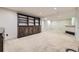 Finished basement with carpeted floors, bar area, and built-in dark wood shelving at 3310 S Oneida Way, Denver, CO 80224