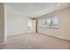 A bright bedroom with a large window, neutral carpet, and an open doorway to the hallway at 3310 S Oneida Way, Denver, CO 80224