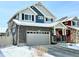 Beautiful two-story home with stone accents, a covered front porch, and a gray two car garage, set in a snowy neighborhood at 1048 Larkspur Dr, Erie, CO 80516