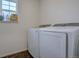 Bright laundry room featuring modern, white front load washer and dryer under a sunny window at 1048 Larkspur Dr, Erie, CO 80516