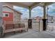 Cozy covered front porch with a wooden bench, stone columns, and a view of the neighborhood street in winter at 1048 Larkspur Dr, Erie, CO 80516