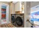 Modern laundry room with front-load washer and dryer, custom cabinets, and adjacent doorway at 11551 W 103Rd Dr, Broomfield, CO 80021